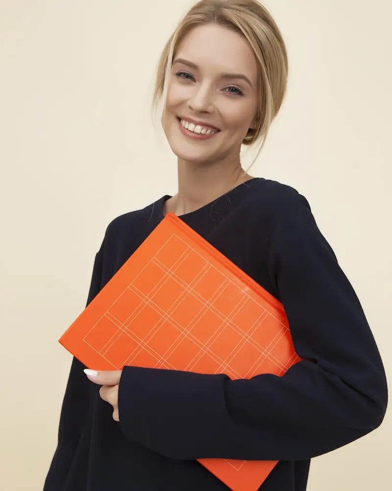 Smiling student holding an orange folder